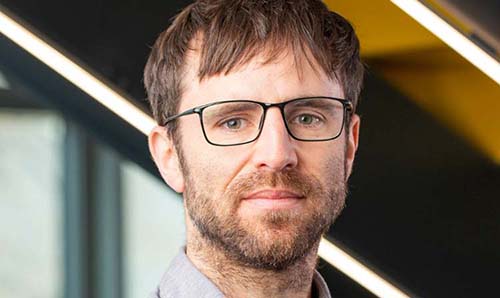 Bearded man with glasses looking directly at camera